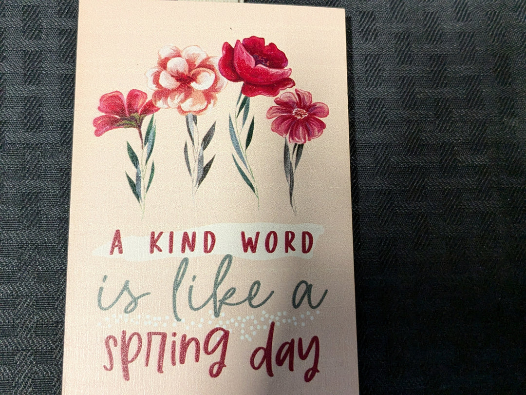 Decorative painted block featuring the phrase 'A kind word is like a spring day.' Perfect for home decor, inspirational gifts, and spring-themed decorations. Ideal for uplifting any space with positive affirmations.